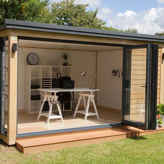 looking into a home office garden pod through open doors showing an office desk and computer laptop
